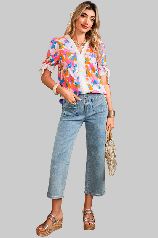 Woman wearing a colorful floral blouse and blue jeans on a gray background