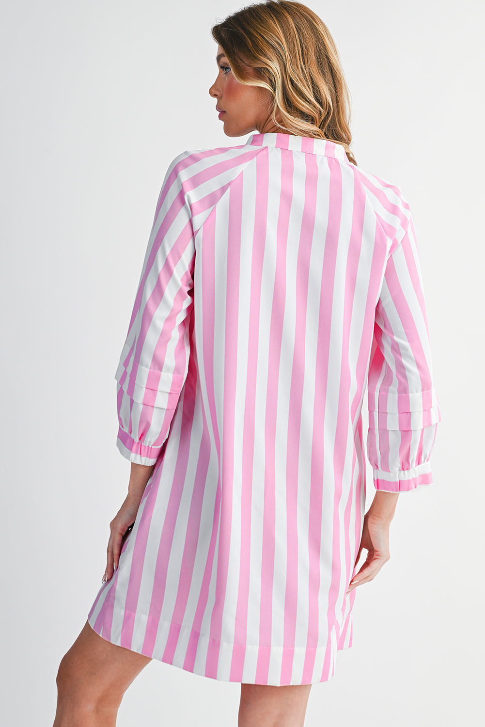 Woman wearing a pink and white striped dress against a plain background