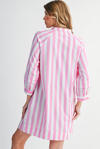 Woman wearing a pink and white striped dress against a plain background