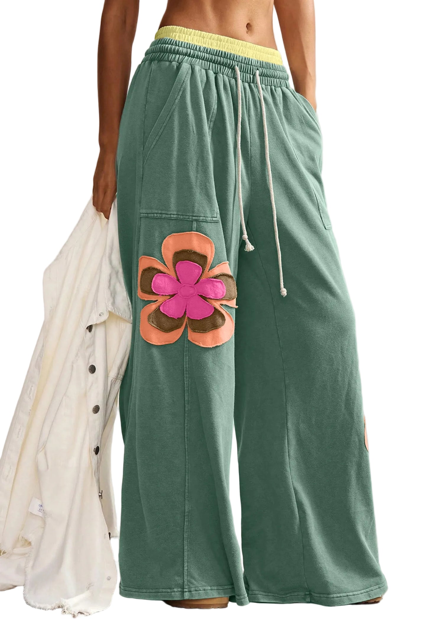 A front-facing product shot of the forest green wide-leg lounge pants, featuring the large peach and brown flower patches and the yellow drawstring waist.