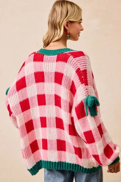 Person wearing a red and pink checkered sweater with green accents on a beige background