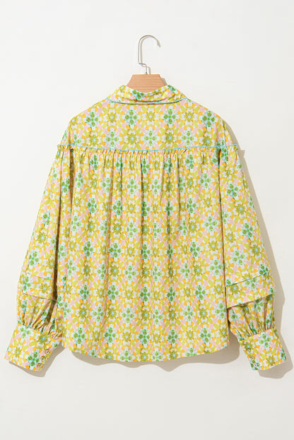 Back view of a green and yellow floral blouse with balloon sleeves on a hanger.