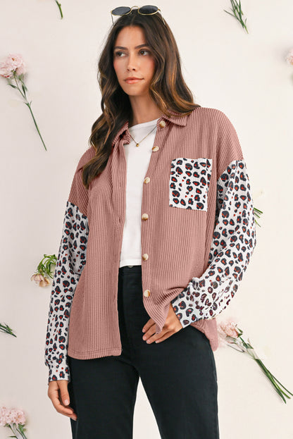 Woman wearing a pink button-up shirt with leopard print sleeves against a light background