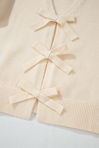 Close-up of a soft knit cardigan with delicate bow-tie details on the front.
