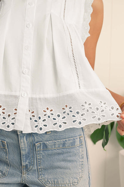 Close-up of a white cotton blouse featuring delicate lace trim and embroidered eyelet hem.
