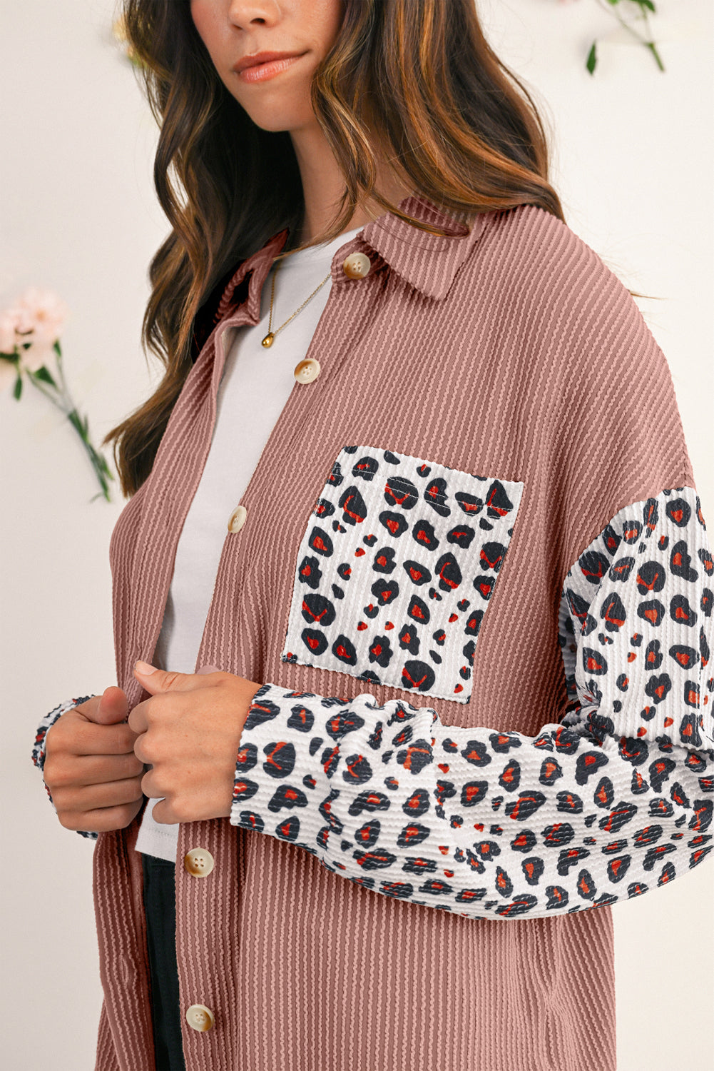 Woman wearing a brown corduroy shirt with leopard print sleeves against a white background