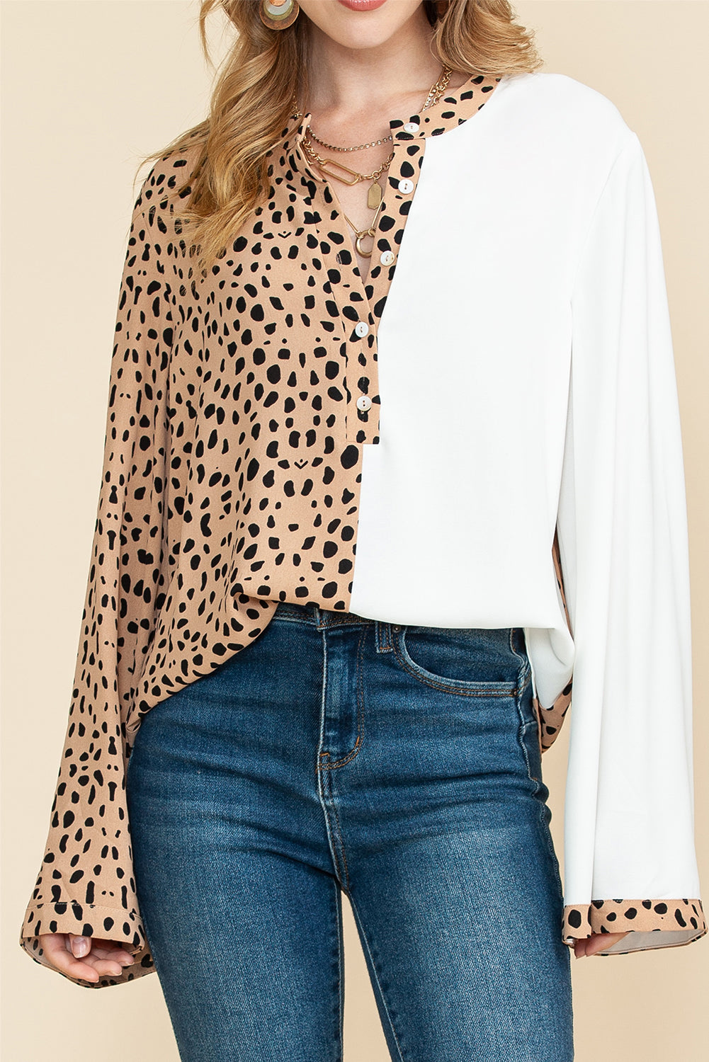 Front view of standing model, wearing khaki leopard print blouse with flared long sleeves, paired with blue jeans for a casual summer look