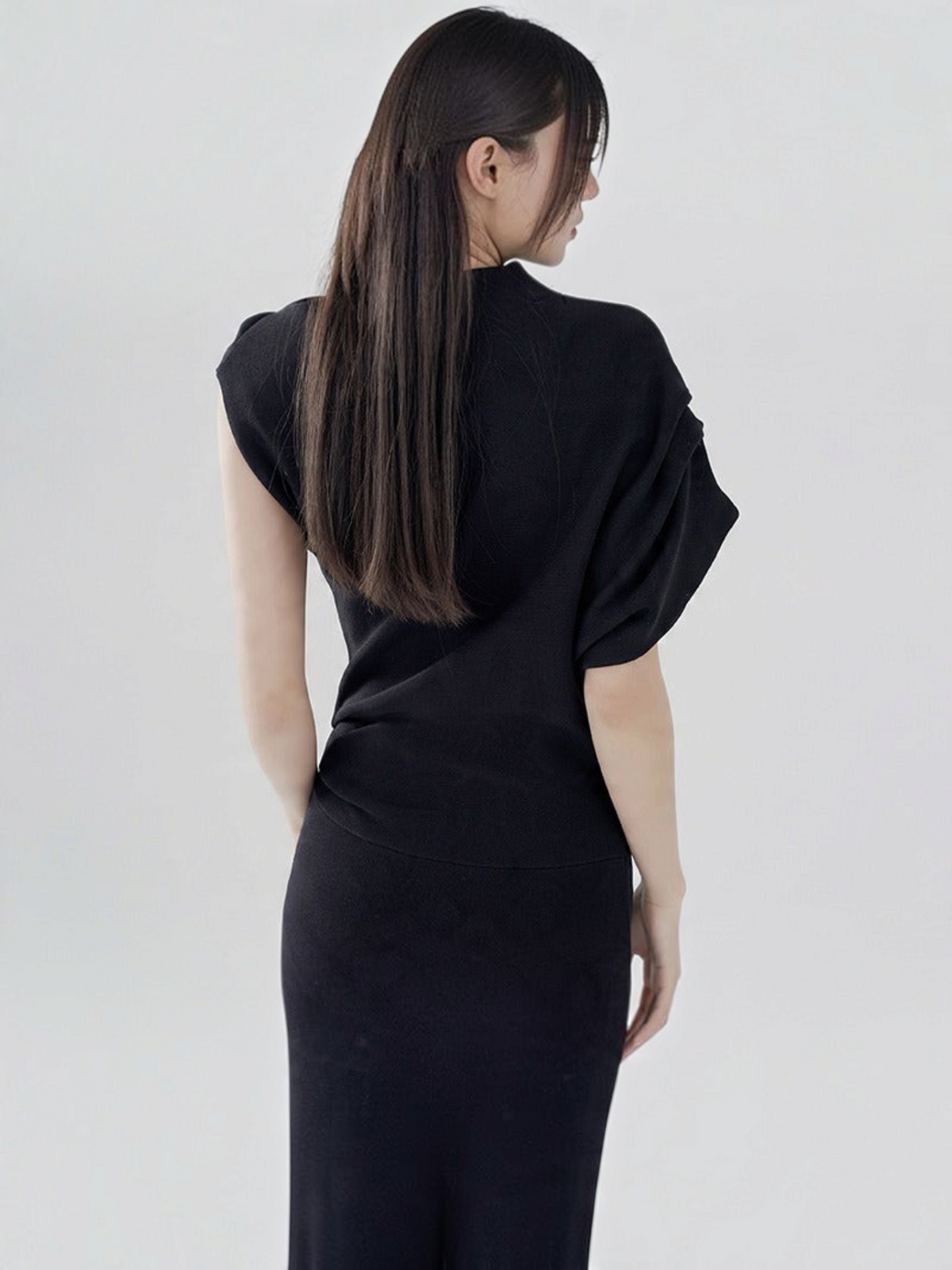 Catherine Martin black two-piece set featuring an asymmetric batwing sleeve top and fitted midi skirt on a model
