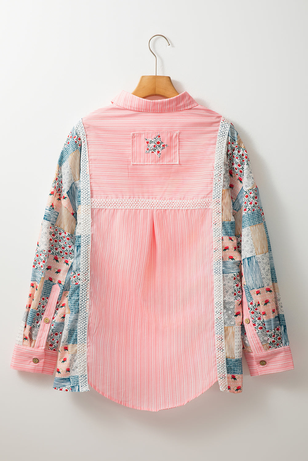 Full back view of a stylish pink floral patchwork long sleeve shirt on a hanger.