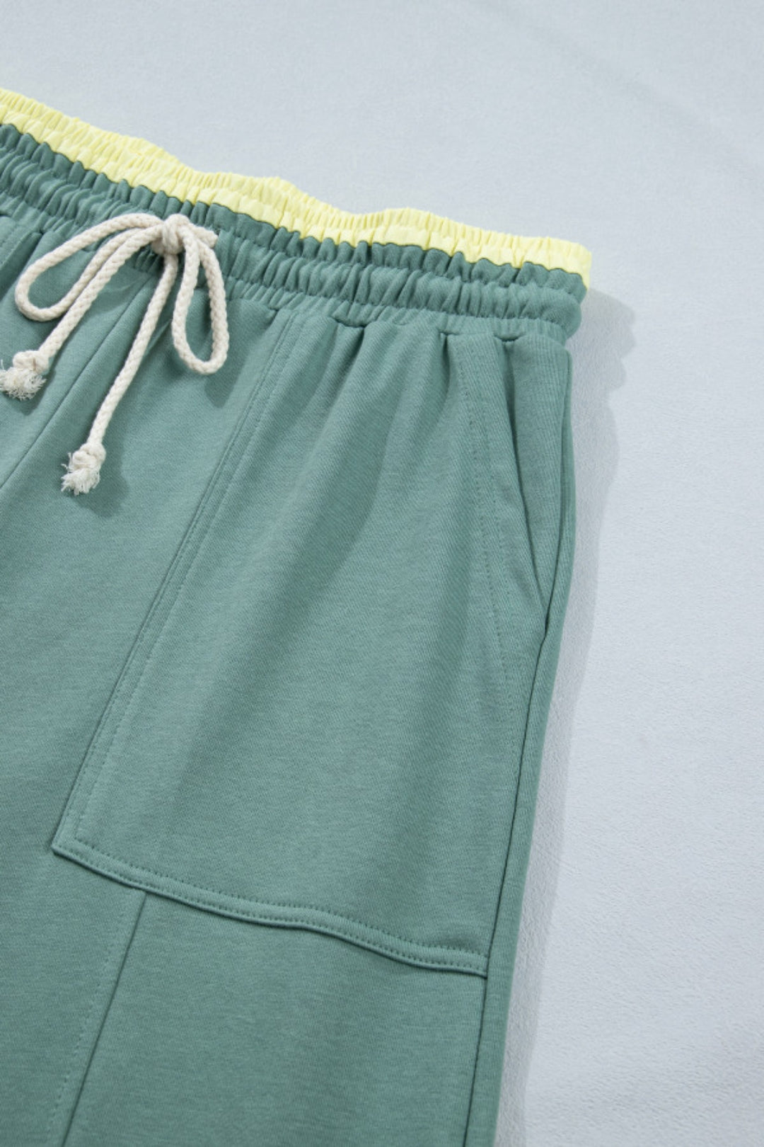 The closed-up view of the forest green patchwork wide-leg pants, highlighting the relaxed fit with self-tie elastic waistband.
