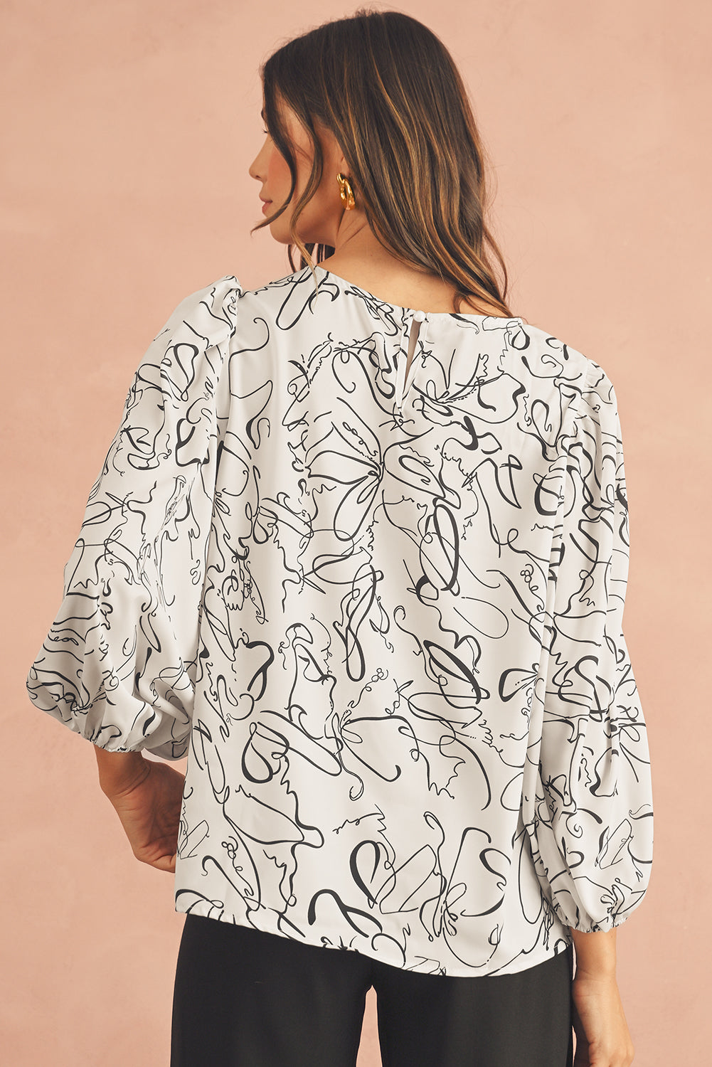 The back view of black and beige blouse, featuring crew and balloon sleeves.