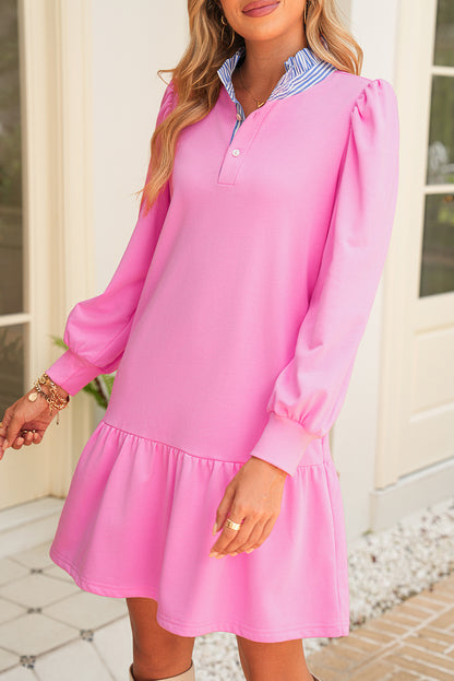 Woman wearing a pink dress with long sleeves and a white collar.
