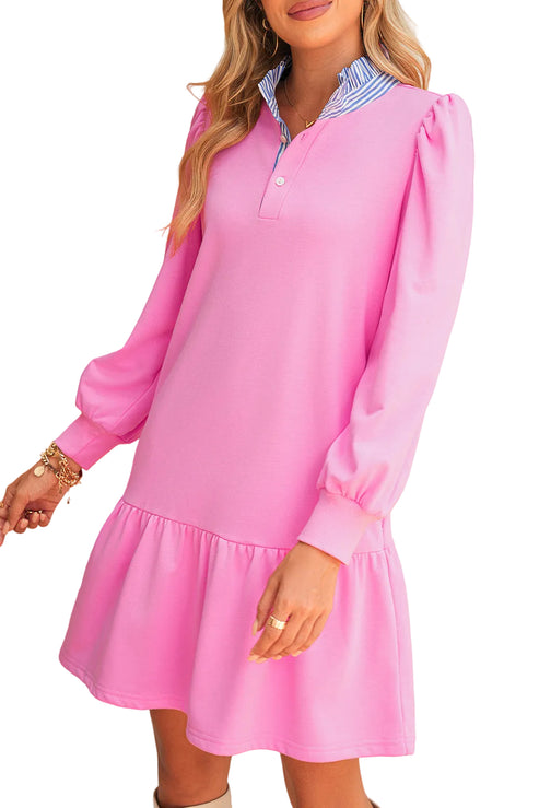 Woman wearing a pink dress with long sleeves and a white collar.