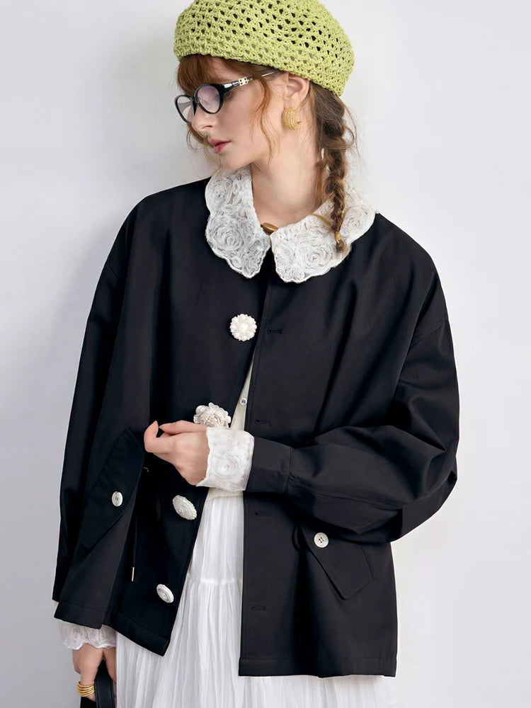 Person wearing a black jacket with white lace collar and cuffs, green knitted hat, and white dress on a light gray background.