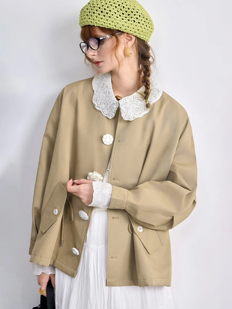 Person wearing a beige coat with white collar and buttons, green knitted hat, and white dress against a plain background.
