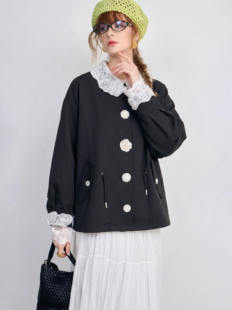 Person wearing a black jacket with white lace details on a plain background