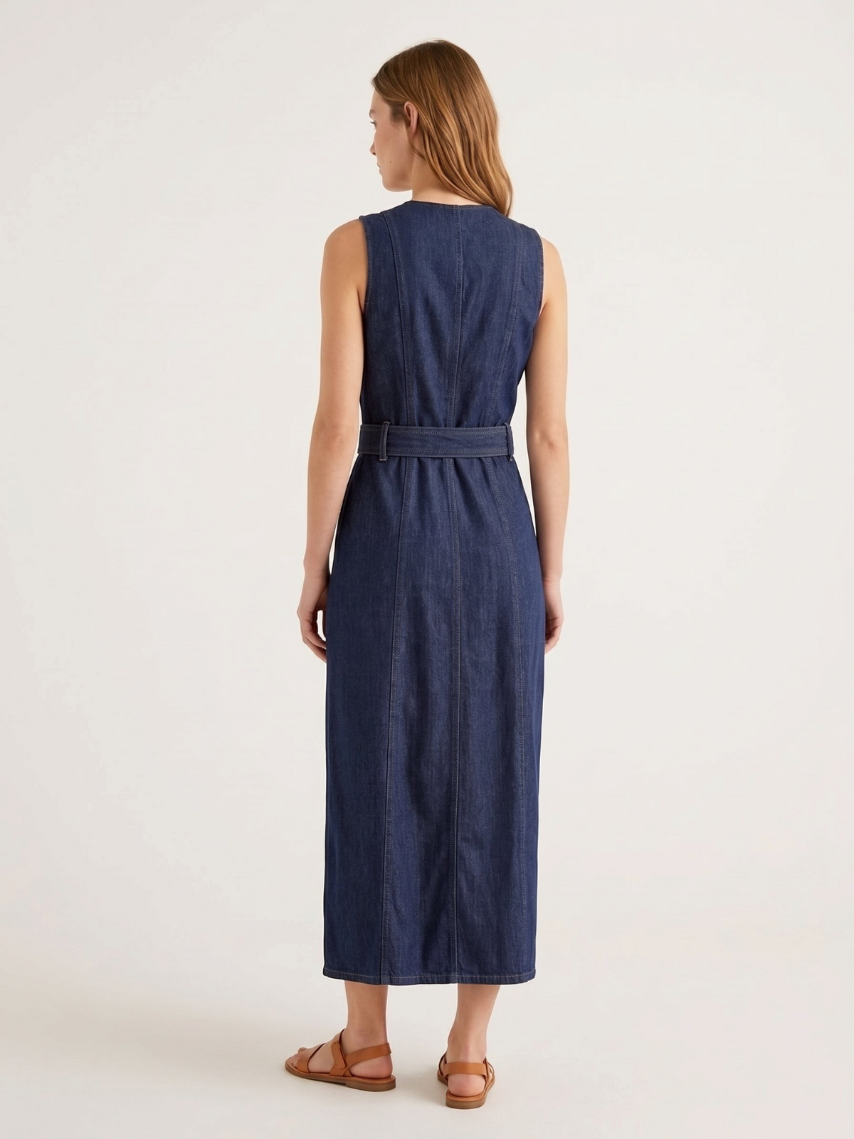Catherine Martin sleeveless dark indigo denim maxi dress seen from the back with vertical seaming and a belted waist.