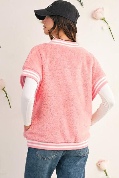 Person wearing a pink varsity jacket with white accents, standing against a light background with flowers.