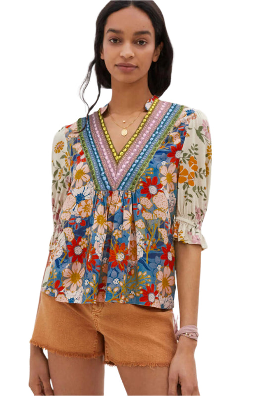 A model standing in a multicolor boho blouse with a V-neck and half sleeves.