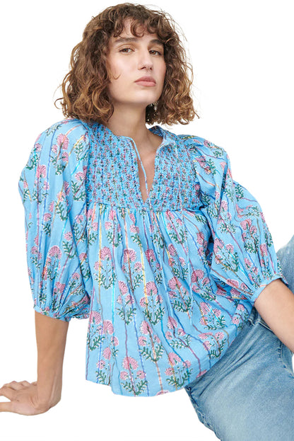 Model sitting in a light blue striped floral blouse with half sleeves, set against a neutral background.