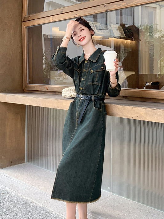 Woman in a green dress holding a coffee cup outside a building.