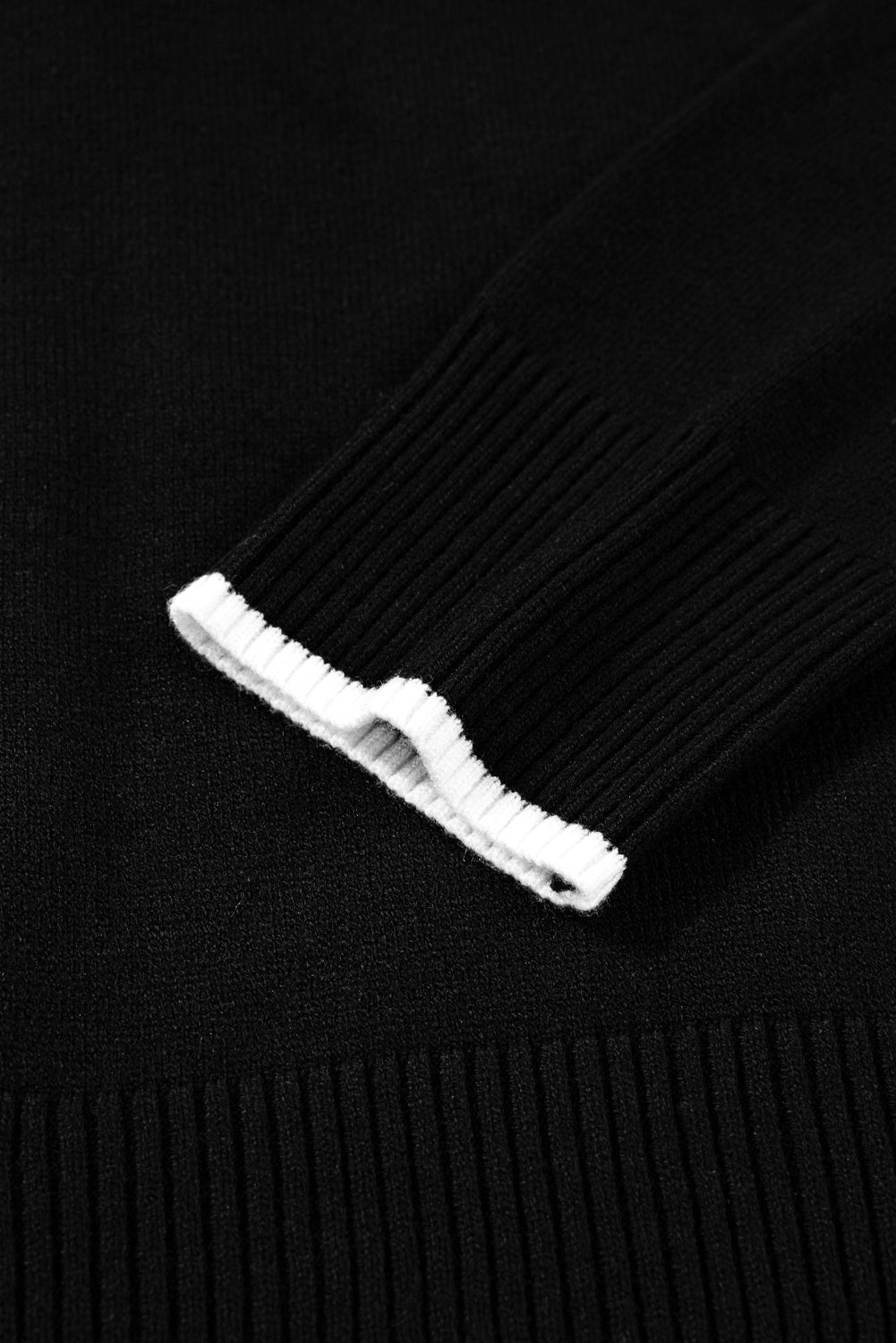 Close-up of a black sweater with a white tag on a black background