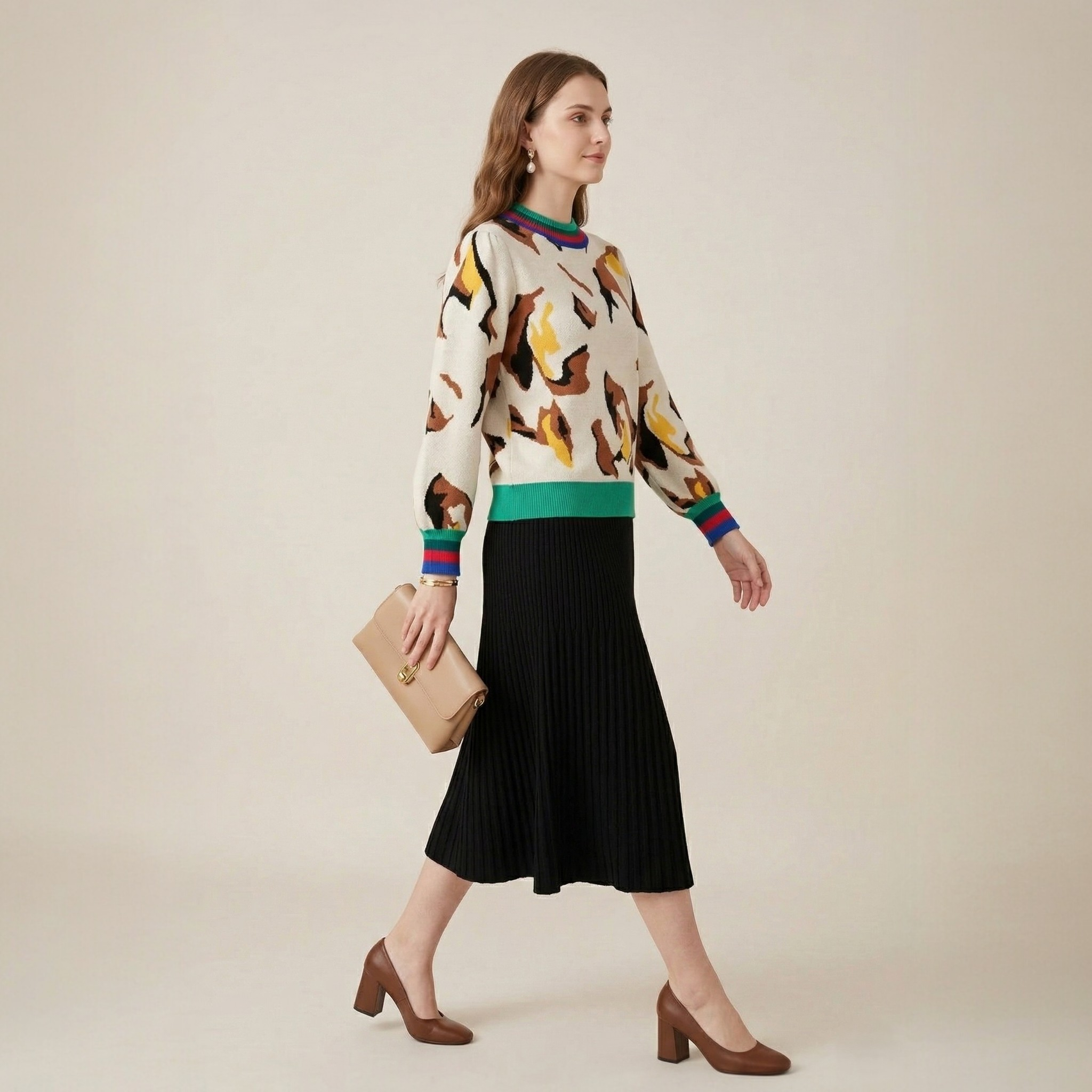 Abstract print stripe trim knit sweater side view model walking with beige clutch styled with black pleated midi skirt and brown block heels