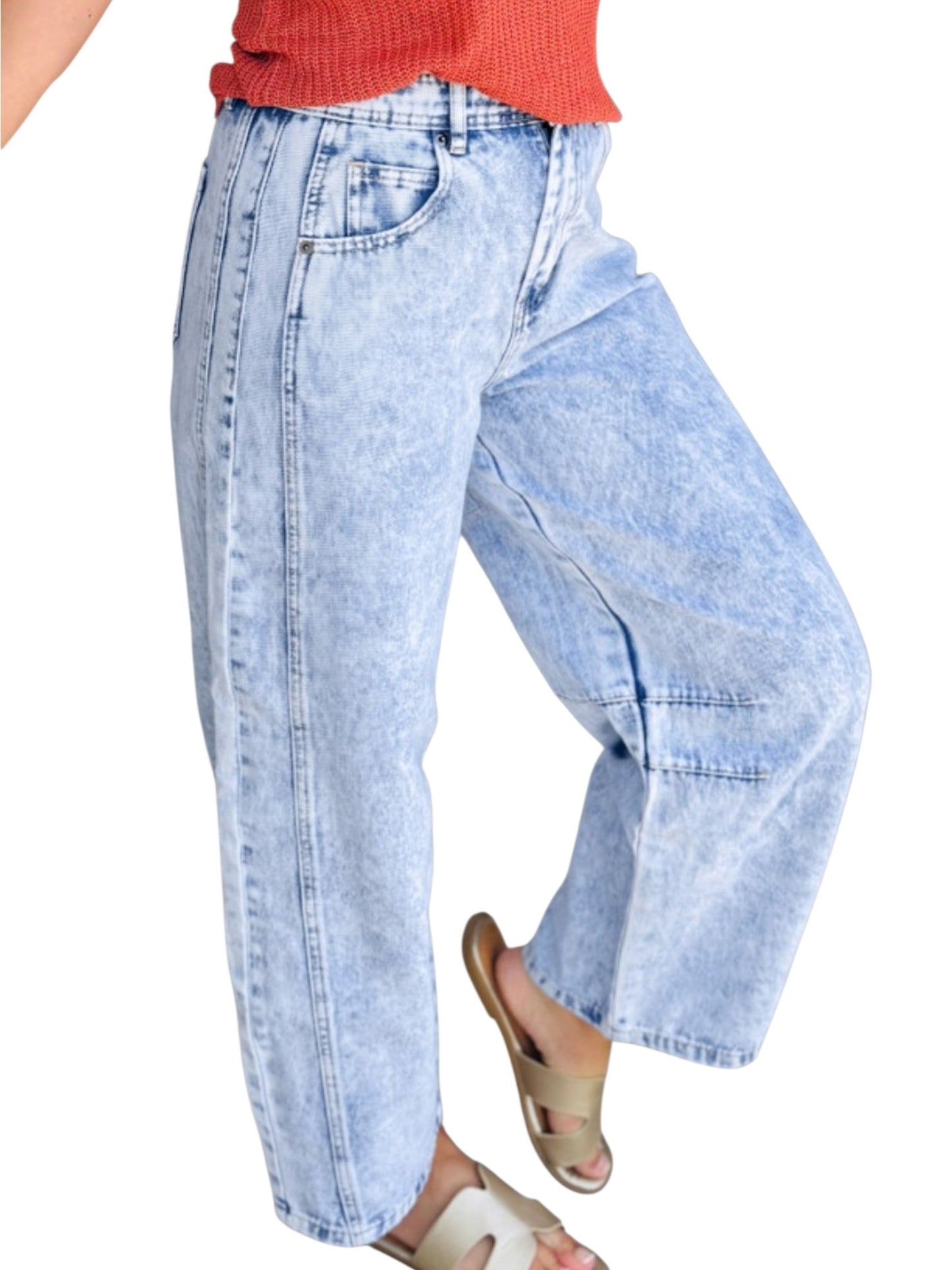 Light blue acid-wash wide-leg jeans shown on a model from the waist down, paired with a coral-red ribbed top and beige slide sandals, against a plain white background.