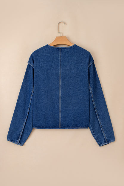 Blue denim jacket on a hanger against a beige background