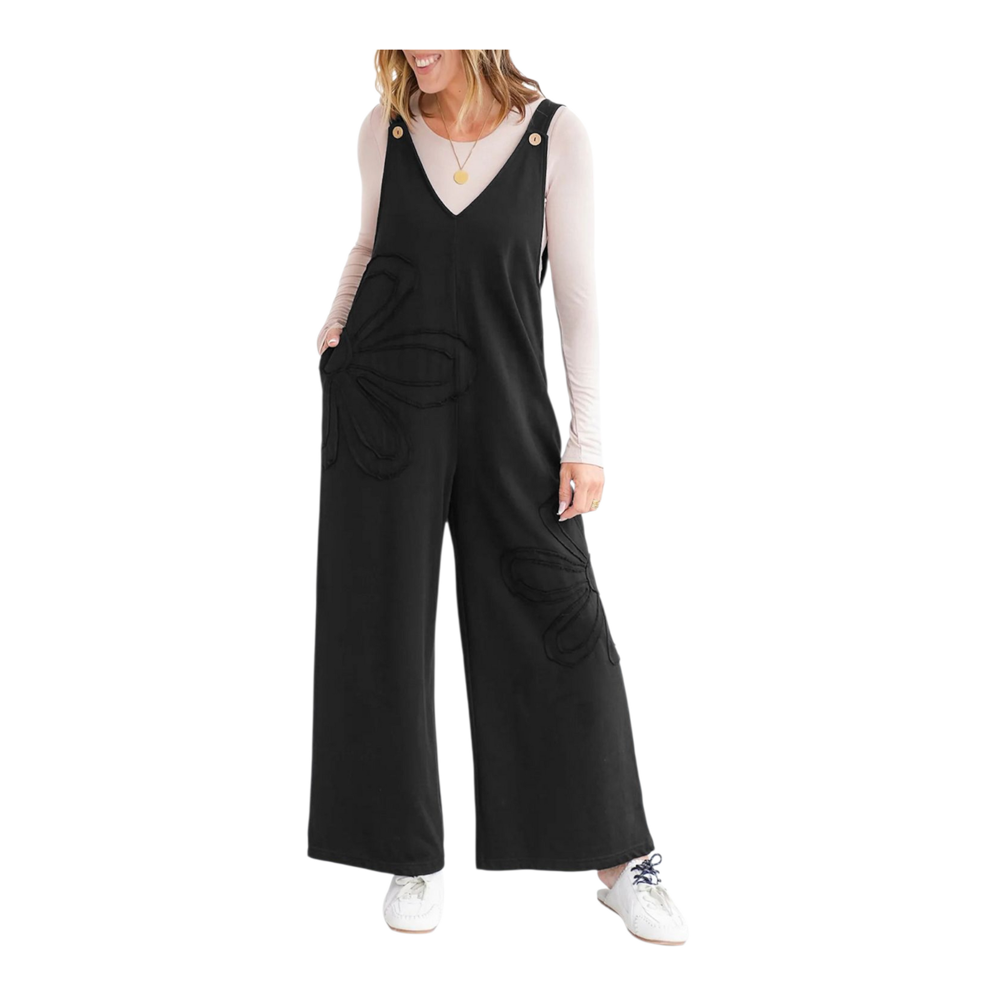 Woman wearing black overalls with a white long-sleeve shirt underneath on a white background