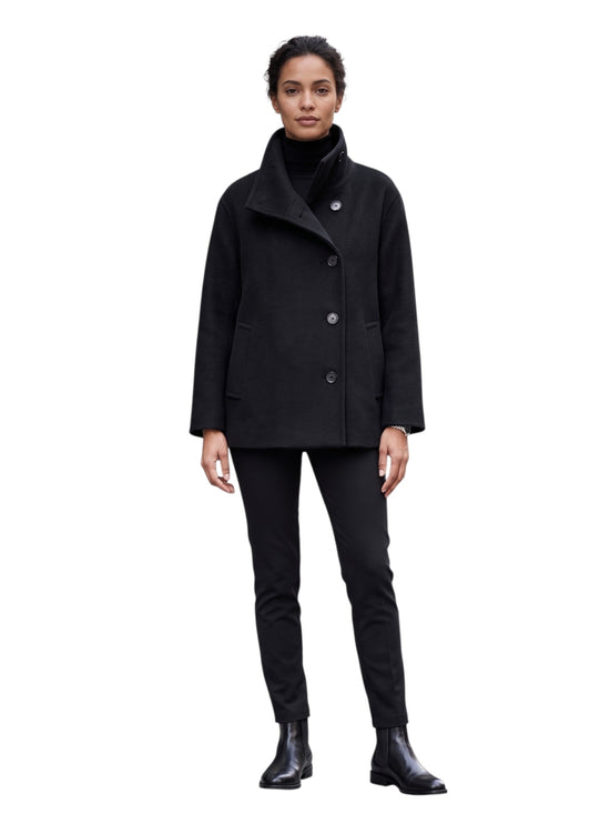 Woman wearing a black coat and pants on a white background front profile view