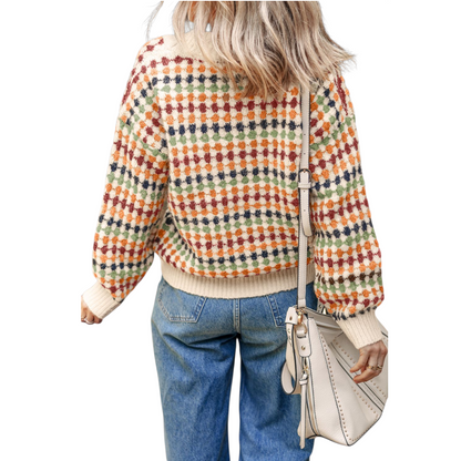 Person wearing a colorful checkered sweater and blue jeans, holding a beige handbag on a white background