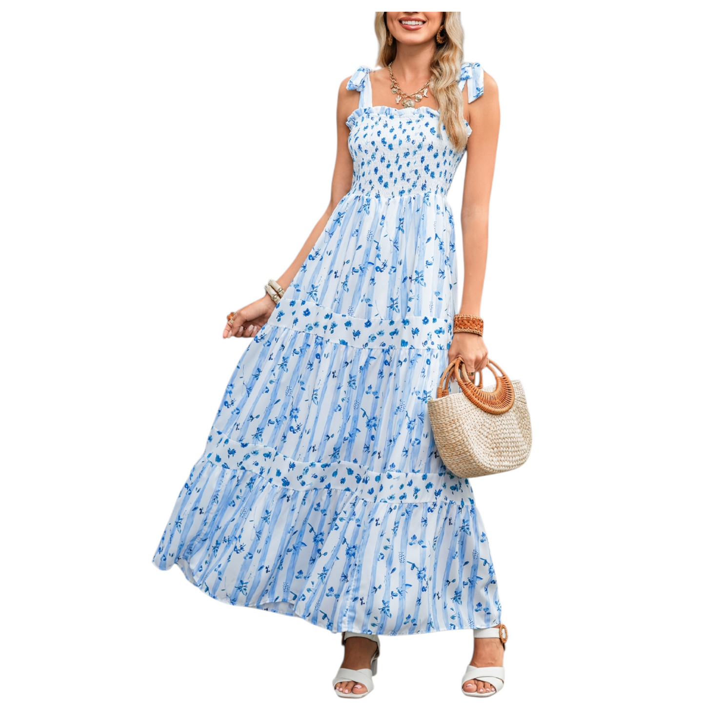 A woman wearing a blue and white striped maxi dress with a floral print, featuring a shirred bodice, tie-up ribbon shoulder straps, and a tiered flowy skirt.