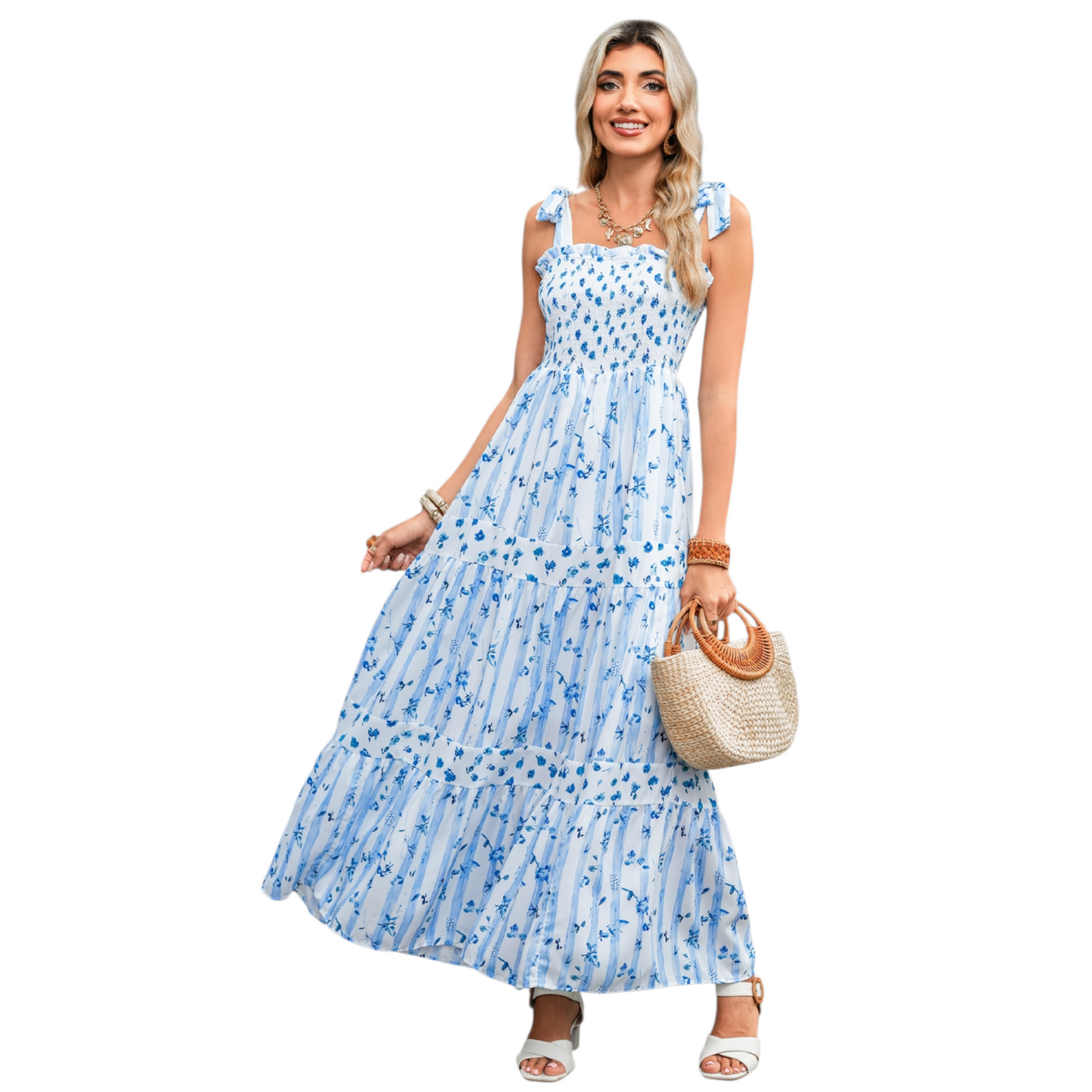 A woman wearing a blue and white striped maxi dress with a floral print, featuring a shirred bodice, tie-up ribbon shoulder straps, and a tiered flowy skirt.