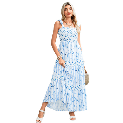 A woman wearing a blue and white striped maxi dress with a floral print, featuring a shirred bodice, tie-up ribbon shoulder straps, and a tiered flowy skirt.
