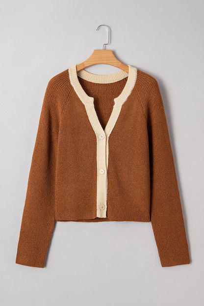 Brown sweater with cream buttons on a wooden hanger against a gray background