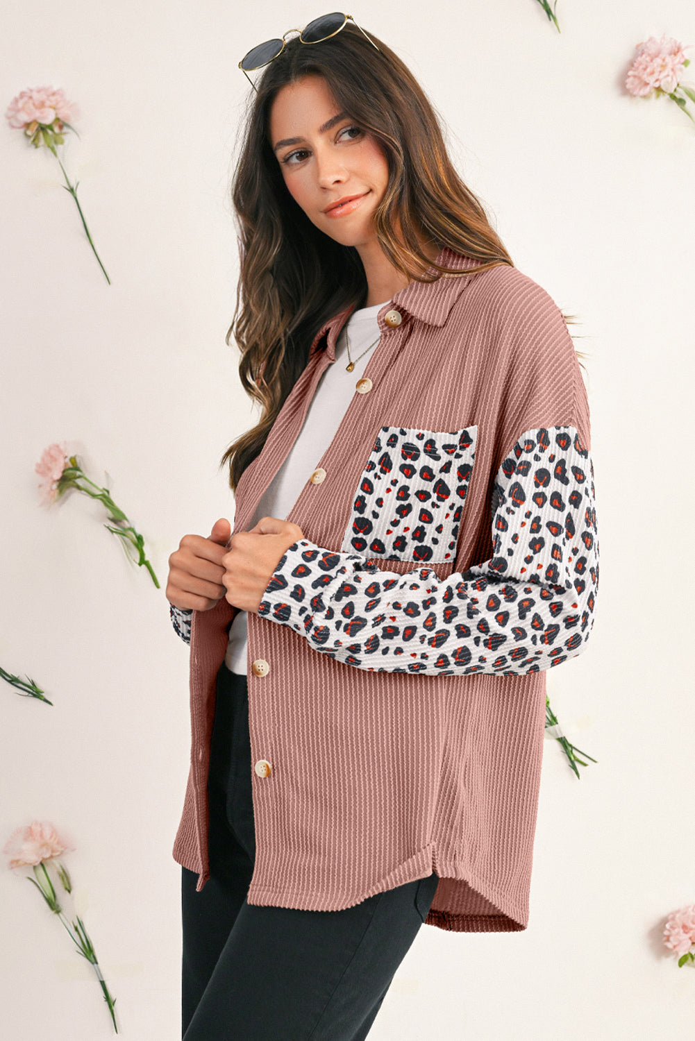 Woman wearing a pink shirt with leopard print sleeves against a floral background