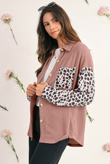 Woman wearing a pink shirt with leopard print sleeves against a floral background