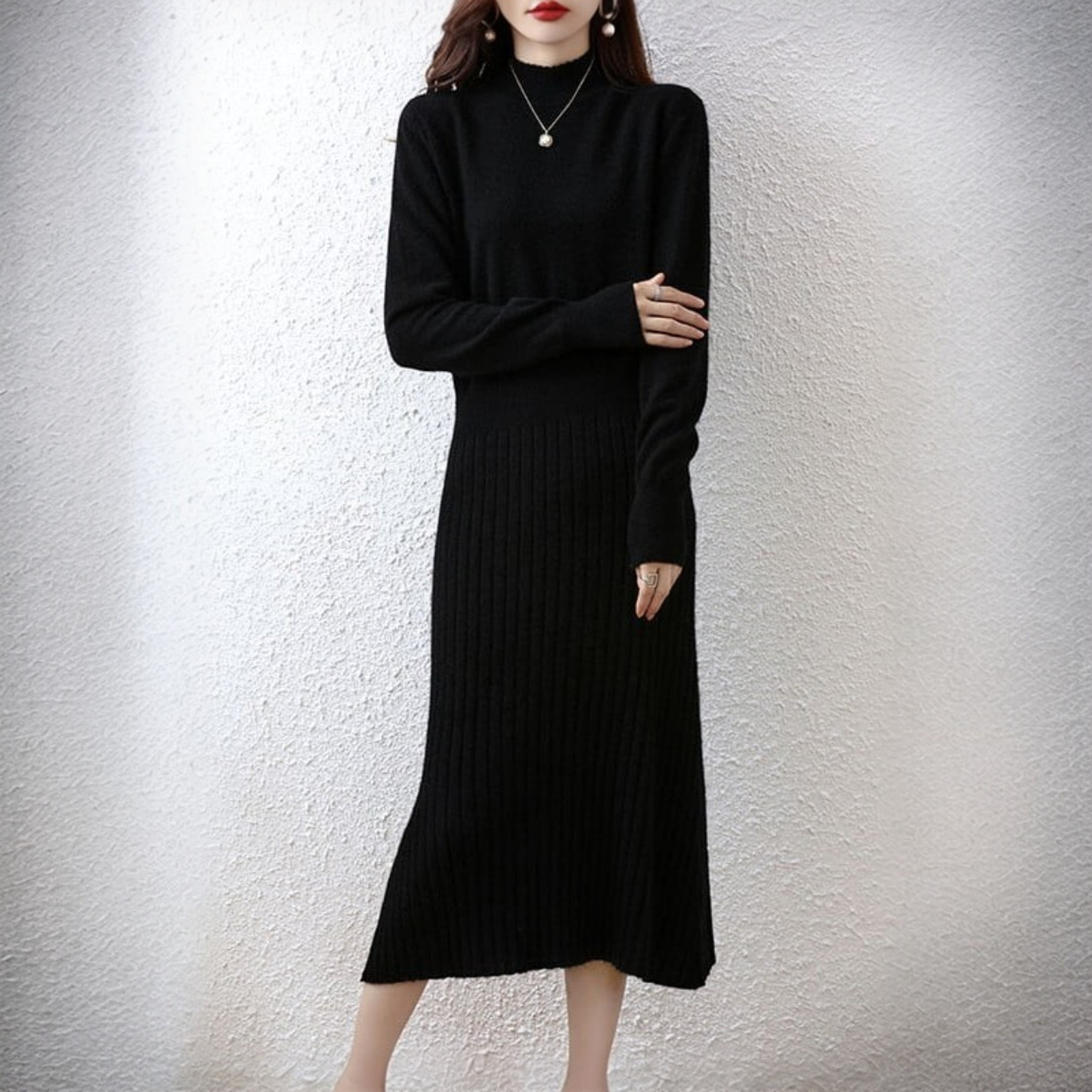 Woman wearing a black ribbed knit dress against a plain background