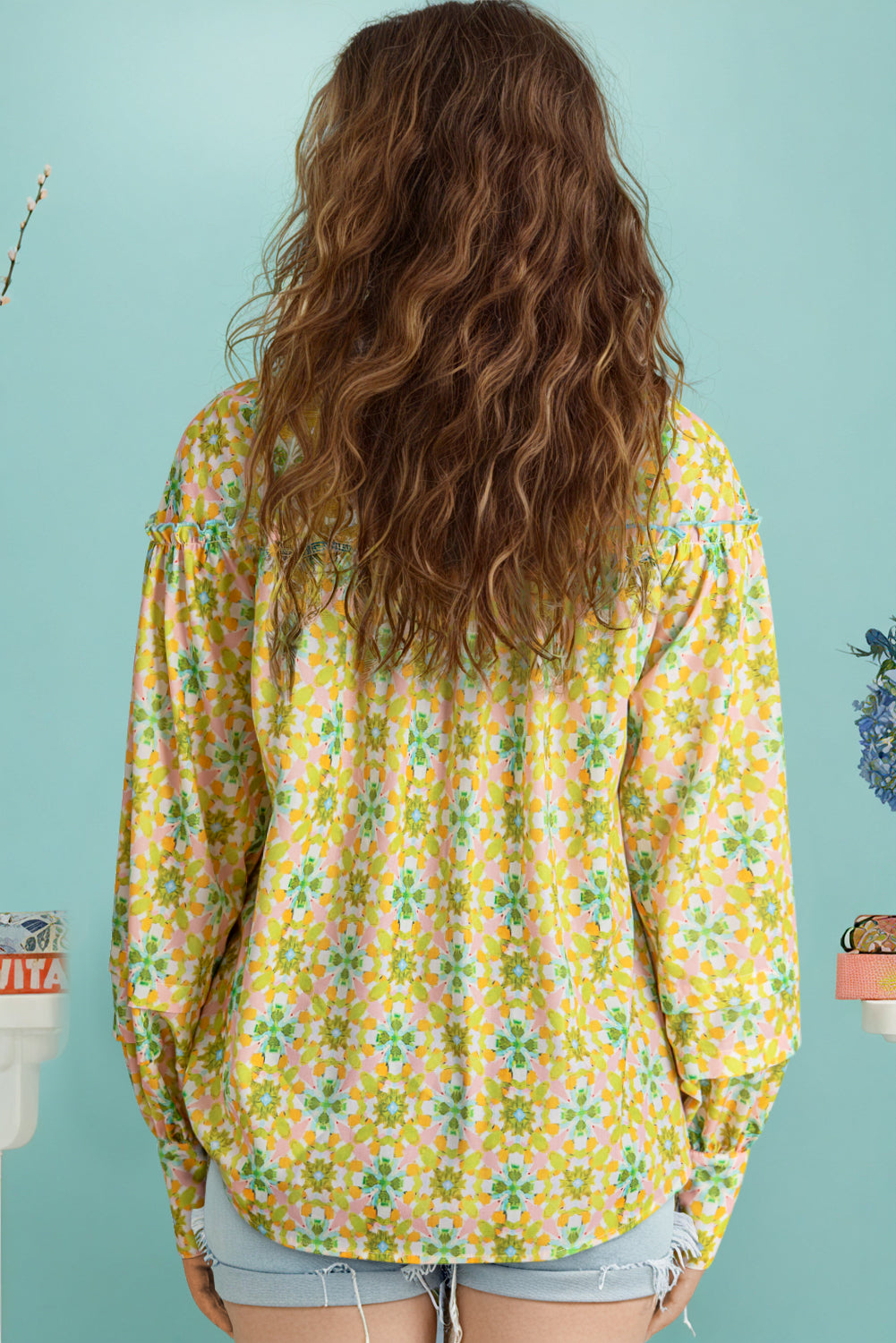 Back view of a green and yellow floral blouse with balloon sleeves.