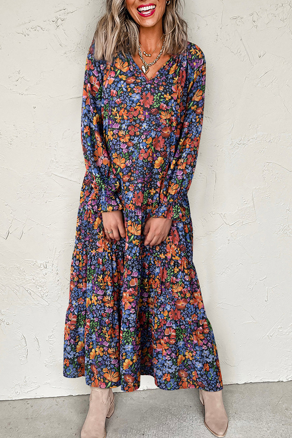Woman wearing a long floral dress against a white wall