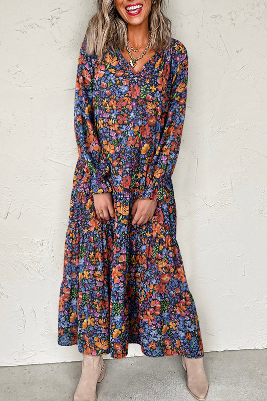 Woman wearing a long floral dress against a white wall