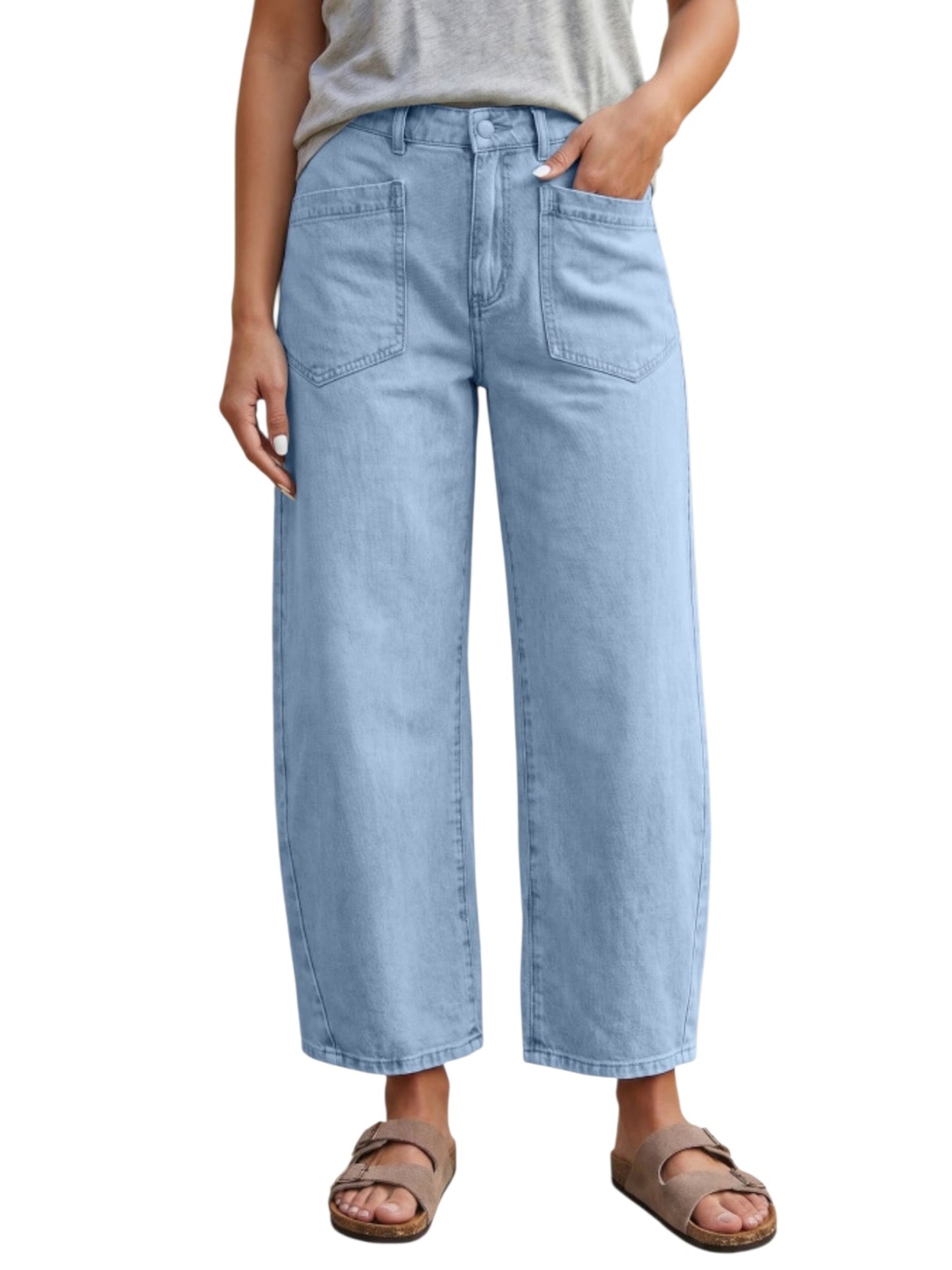 A person wearing light-wash blue wide-leg cropped jeans with a gray top and brown slide sandals, shown from the waist down on a plain white background.