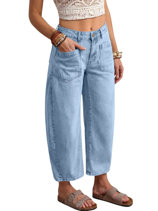 A person wearing light-wash blue cropped wide-leg denim jeans with front patch pockets, paired with brown slide sandals and bracelets, shown against a plain white background.