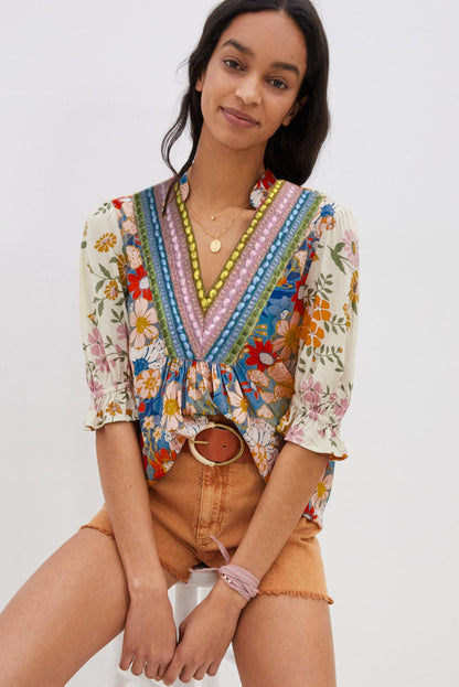 A model sitting in a multicolor boho blouse with a V-neck and half sleeves.