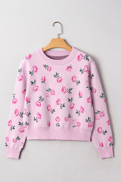 Pink sweatshirt with floral patterns on a wooden hanger against a light gray background