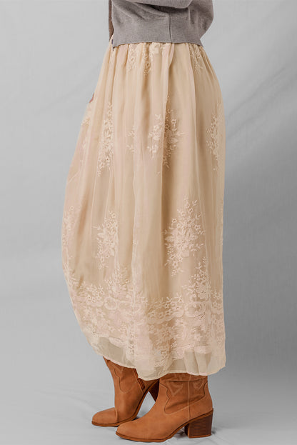 Beige lace skirt worn with brown boots on a gray background