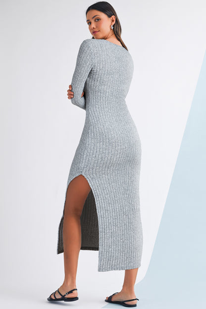 Woman wearing a gray ribbed dress with a slit on a white background