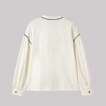 Rear view of a relaxed-fit cream blouse showcasing voluminous bishop sleeves and horizontal black contrast trim across the shoulders.