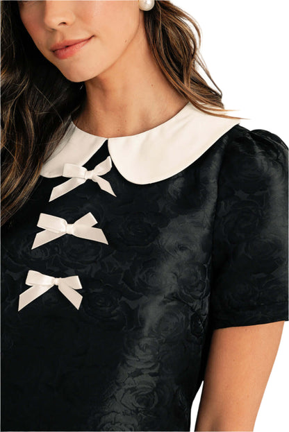 Detail of the high-quality fabric used in the elegant black mini dress. Front detail view.